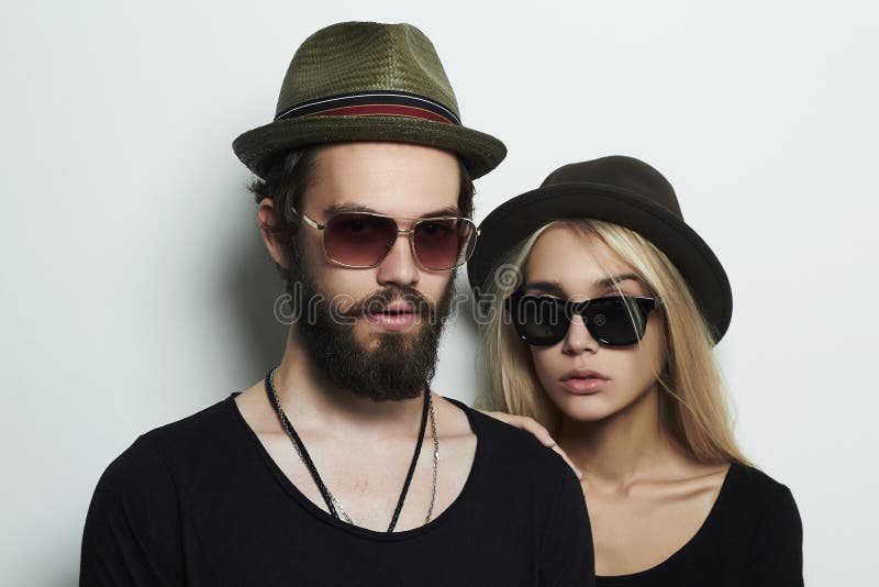 Beautiful couple in hat wearing trendy glasses together. Hipster boy and girl