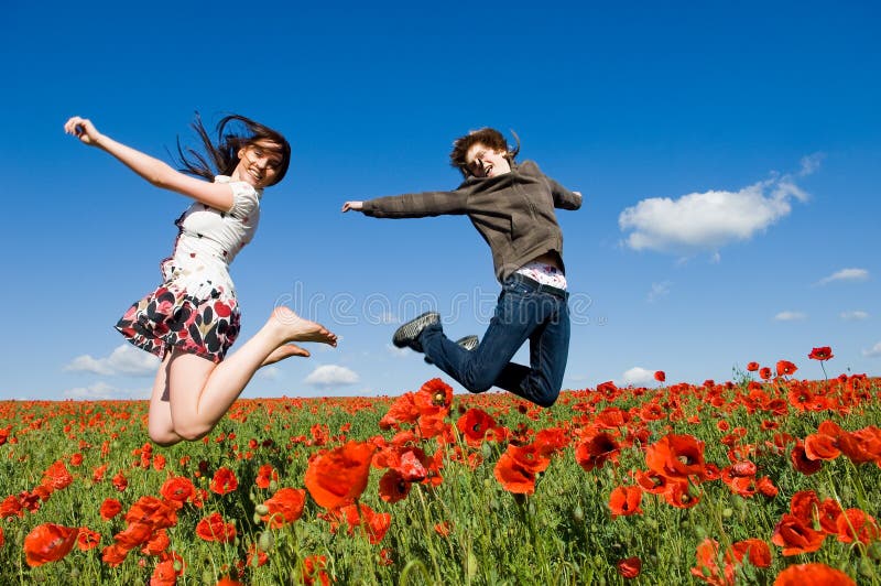 Beautiful couple jumping in the poppy field