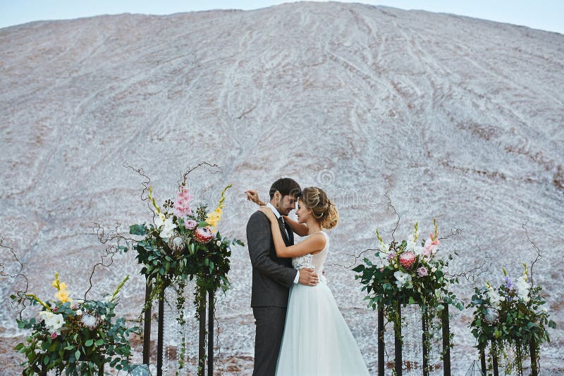 A beautiful couple of lovers at a white desert, a young woman with a wedding hairstyle in a stylish dress and handsome royalty free stock photo A beautiful couple of lovers at a white desert, a young woman with a wedding hairstyle in a stylish dress and handsome royalty free stock photo