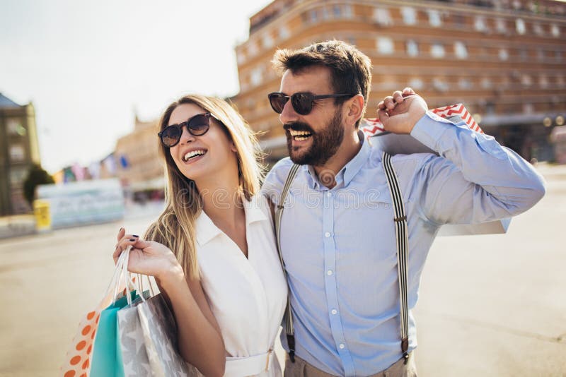Couple with shopping bags is talking and smiling while doing shopping in the city