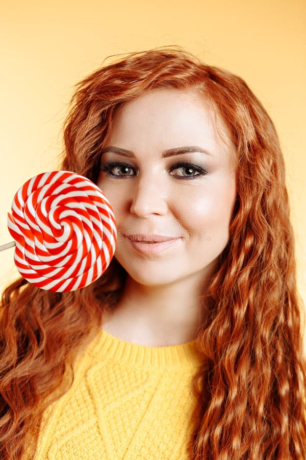 Beautiful Curly Redhead Woman Holding A Red White Lollipop On White