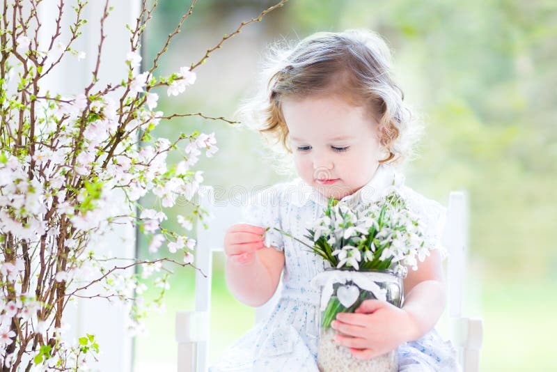 Beautiful curly toddler girl with first spring flowers