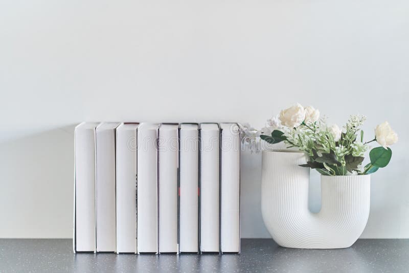 Beautiful curved vase with flowers close-up. Collection of books. Flowers in interior design. Cozy house. stock images Beautiful curved vase with flowers close-up. Collection of books. Flowers in interior design. Cozy house. stock images