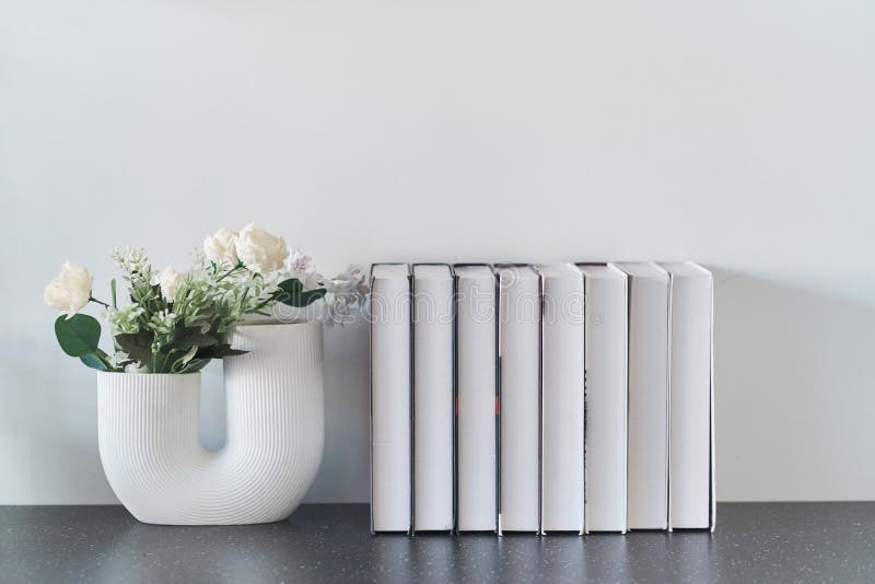 Beautiful curved vase with flowers close-up. Collection of books. Flowers in interior design. Cozy house. royalty free stock image Beautiful curved vase with flowers close-up. Collection of books. Flowers in interior design. Cozy house. royalty free stock image
