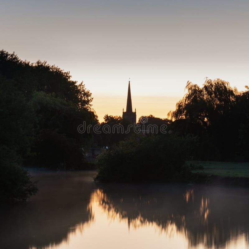 Beautiful dawn landscape image of River Thames at Lechlade-on-Thames in English Cotswolds countryside with church spire in