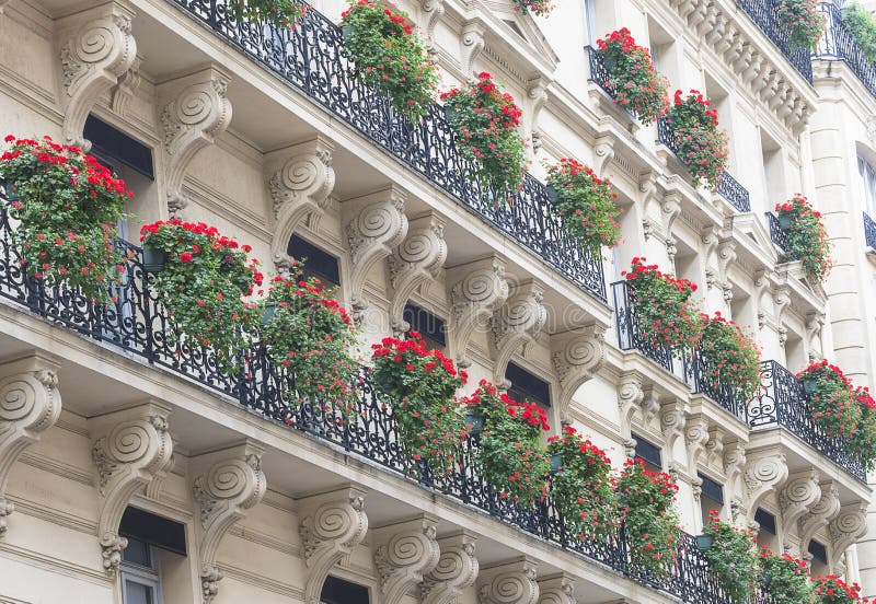 Beautiful decorated balconies of haussmann`s building with red flowers