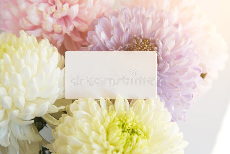 Beautiful delicate bouquet of multicolored chrysanthemums with a white card with the inscription happy birthday in spanish, happy. Holiday stock photos