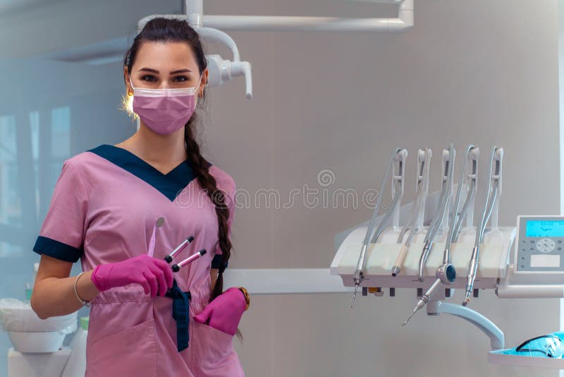 Dentist in Pink Uniform Treat the Teeth of a Patient Stock Photo