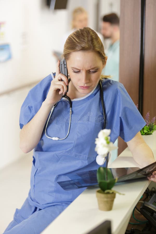 Beautiful doctor talking on mobile phone analyzing xrays royalty free stock image
