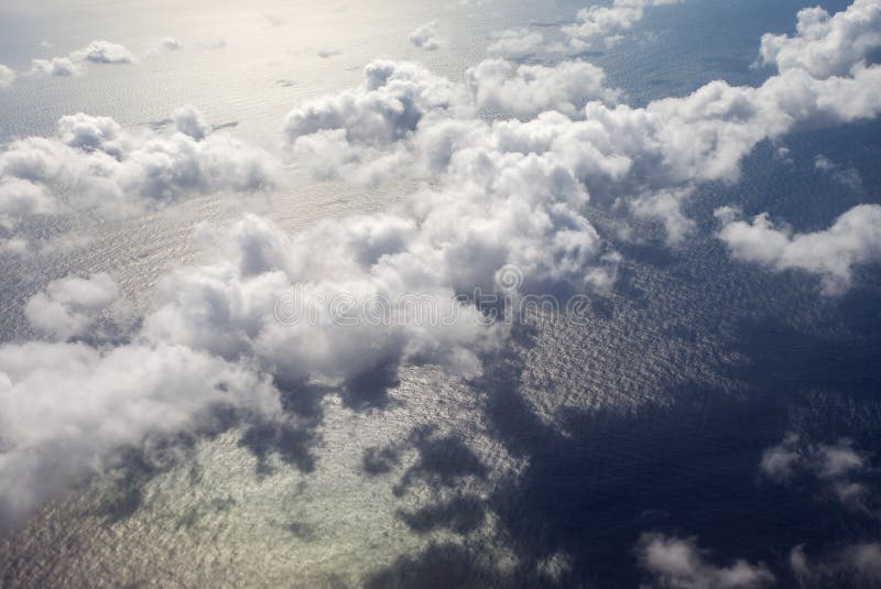 Beautiful, dramatic a group of clouds in the sky over the ocean viewed from a height from inside an airplane. Airplane height stock images, royalty-free photos and pictures