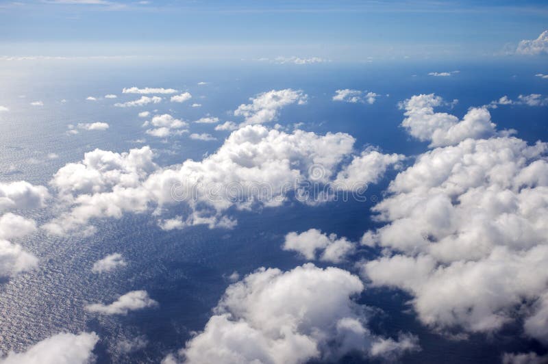 Beautiful, dramatic a group of clouds in the sky over the ocean viewed from a height from inside an airplane. Airplane height stock images, royalty-free photos and pictures