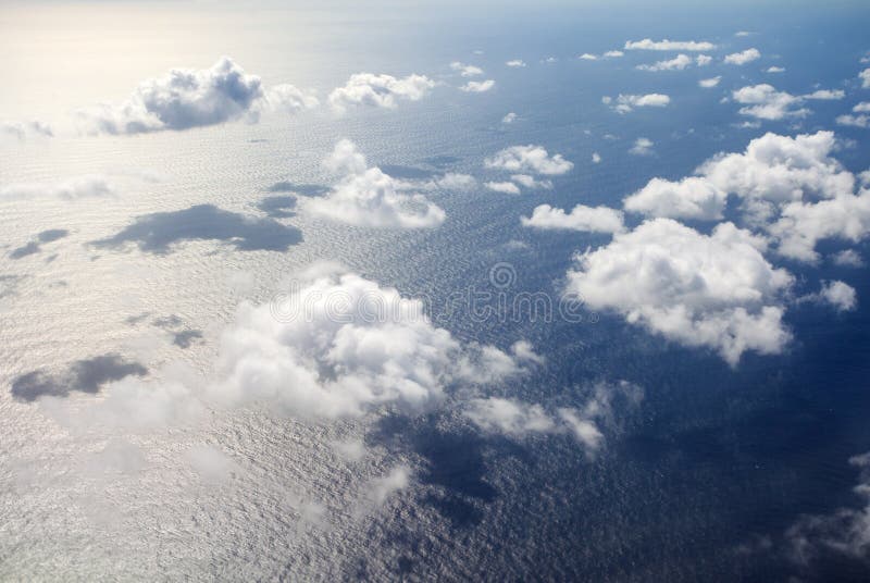 Beautiful, dramatic a group of clouds in the sky over the ocean viewed from a height from inside an airplane. Airplane height stock images, royalty-free photos and pictures