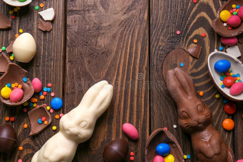 Beautiful Easter composition with chocolate bunnies, eggs and candies on wooden background, top view