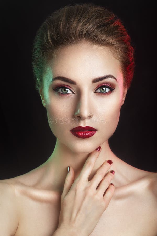 Beautiful elegant young model with red lips and color evening make-up.Woman Face on dark background.Picture taken in the studio.High fashion look.glamor closeup portrait of stylish brunette