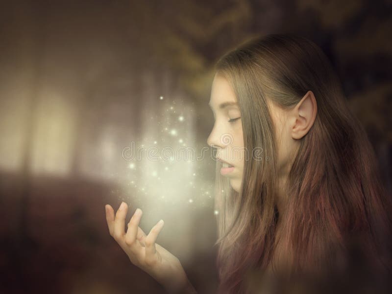 Beautiful elf girl portrait close-up in the forest looking at the glow on her hand. Fantasy photo art stock images Beautiful elf girl portrait close-up in the forest looking at the glow on her hand. Fantasy photo art stock images