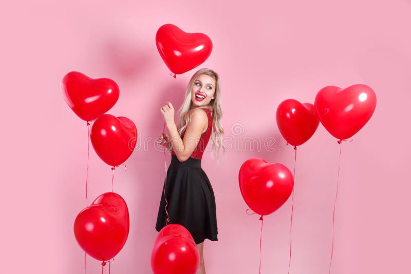 Beautiful emotional woman in elegant dress with red heart ballons on pink background royalty free stock images Beautiful emotional woman in elegant dress with red heart ballons on pink background royalty free stock images