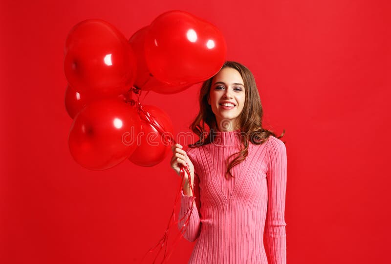 Beautiful emotional girl in pink dress with red ballons on red background