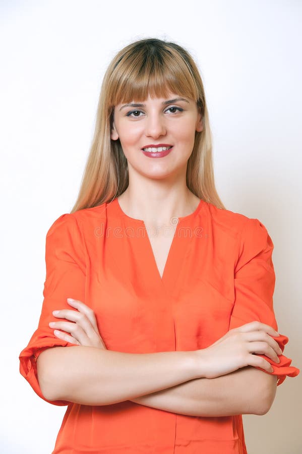 Beautiful European young woman standing with her hands folded.