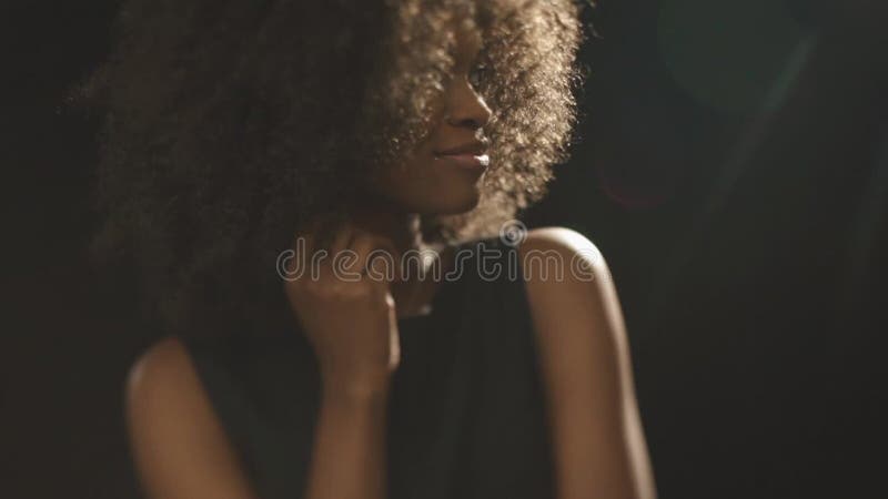 Beautiful exotic shy young black woman covers face by hand and flirting