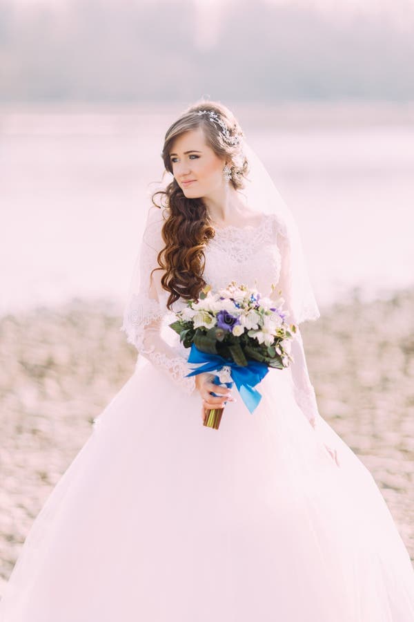 Beautiful fabulous curly bride with stylish bouquet standing on the beach. royalty free stock photos Beautiful fabulous curly bride with stylish bouquet standing on the beach. royalty free stock photos