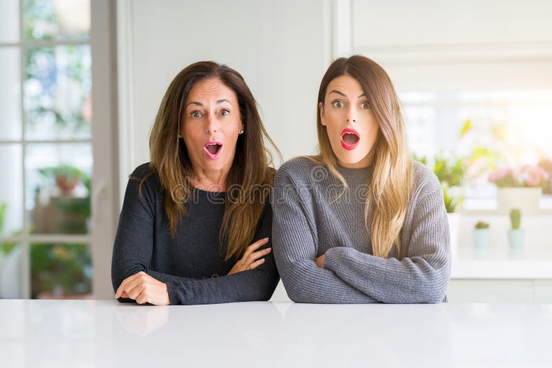 Beautiful Family of Mother and Daughter Together at Home Afraid and Shocked with Surprise