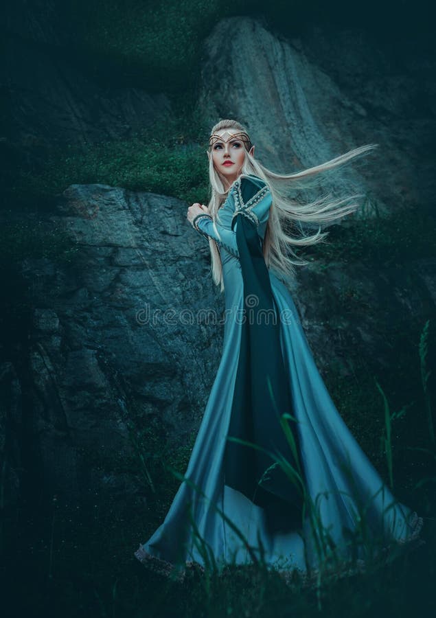 Beautiful fantasy woman elven goddess walks in nature mystical forest. Long creative vintage blue dress, sleeves. Blond