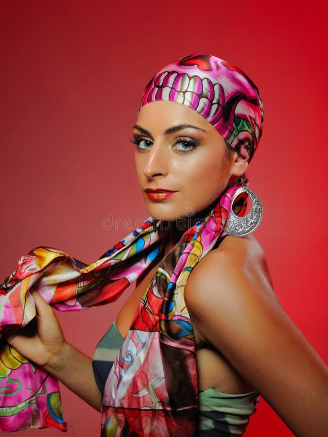 Beautiful fashion woman with bright make-up and hair veil. red background