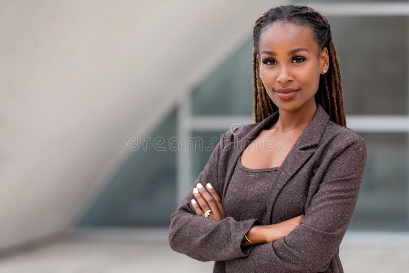 Beautiful female african american business woman CEO in a suit at the workplace, standing confidently with arms folded