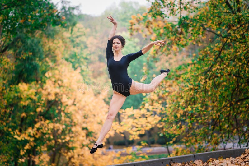 Beautiful female, ballerina, athlete in black bodysuit training in the park