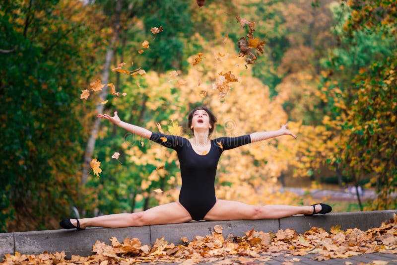 Beautiful female, ballerina, athlete in black bodysuit training in the park