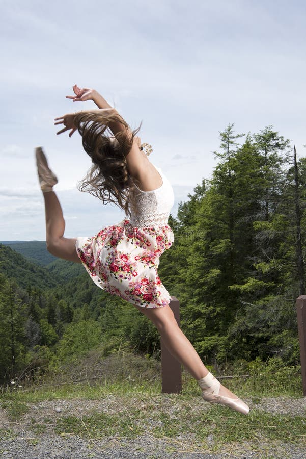 Beautiful female ballerina or dancer leaps outdoors