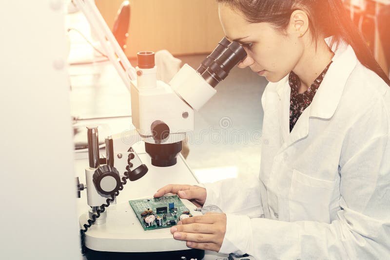 Beautiful female computer expert professional technician examining board computer in a laboratory in a factory royalty free stock images