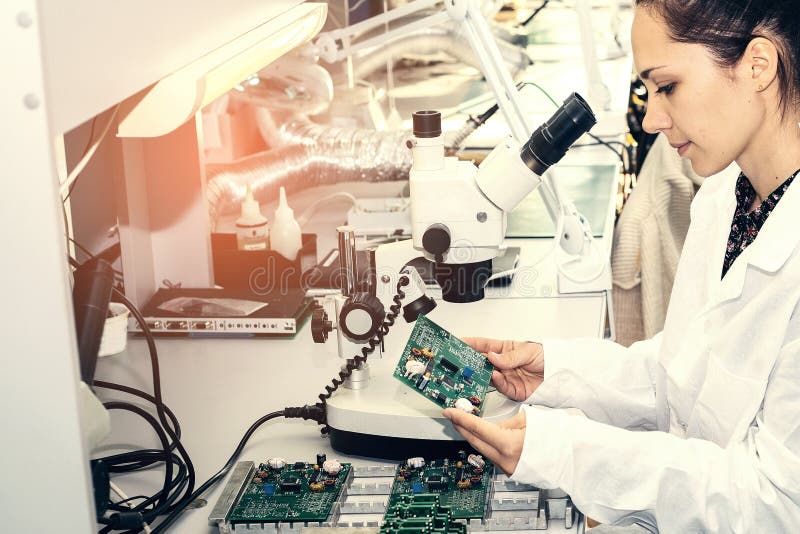 Beautiful female computer expert professional technician examining board computer in a laboratory in a factory royalty free stock photo