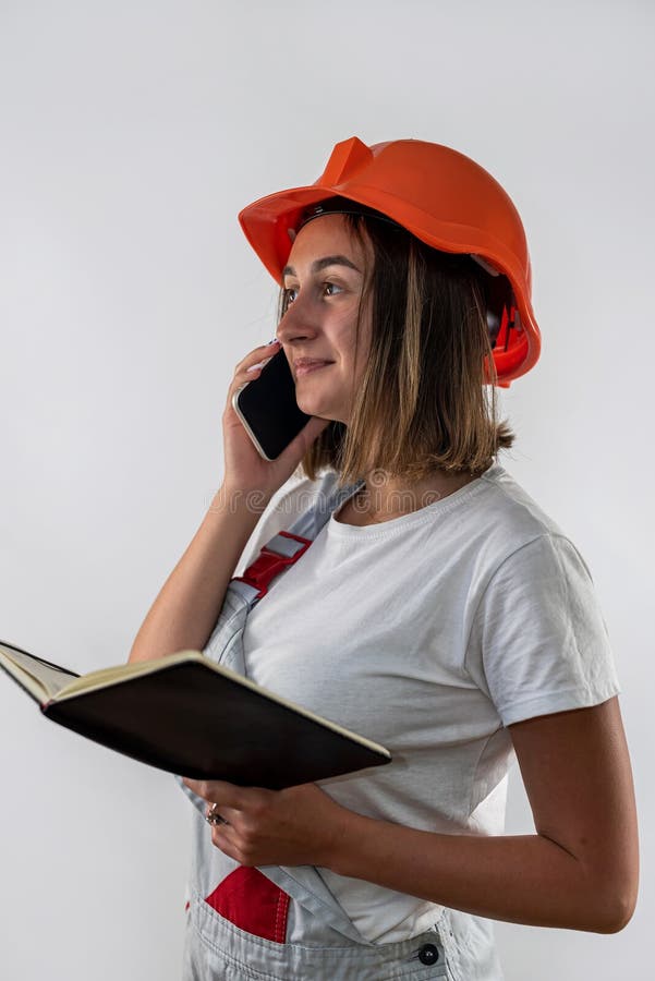 Beautiful female construction worker holding a folder with documents in her hands and smiling royalty free stock photography