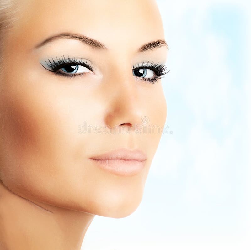 Beautiful female face over blue sky background. Closeup of beautiful female face over abstract blue sky background, bright eye makeup, woman with perfect soft stock photos Beautiful female face over blue sky background. Closeup of beautiful female face over abstract blue sky background, bright eye makeup, woman with perfect soft stock photos
