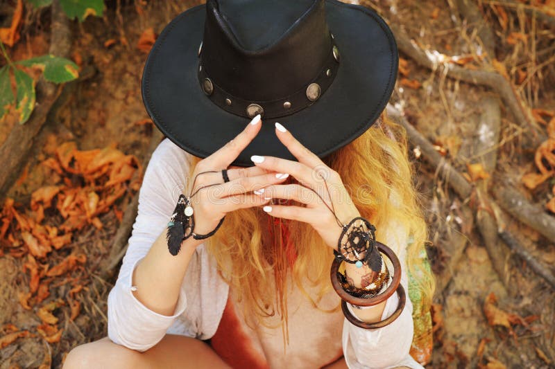 Beautiful female hands with boho chic dreamcatcher bracelets and black leather hat. White manicure, no face, indie style, autumn outdoor stock image Beautiful female hands with boho chic dreamcatcher bracelets and black leather hat. White manicure, no face, indie style, autumn outdoor stock image