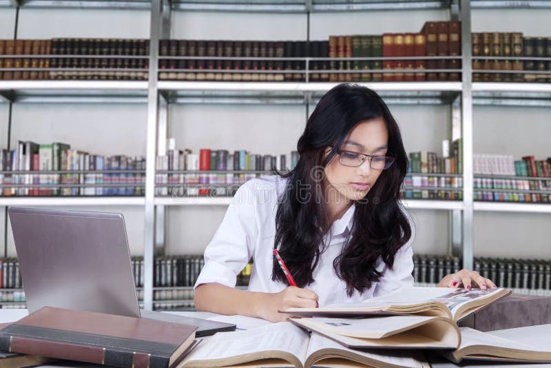 Beautiful female student studying in a library stock photo Beautiful female student studying in a library stock photo
