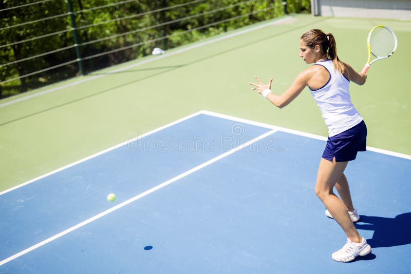 Beautiful female tennis player in action, hitting a forehand