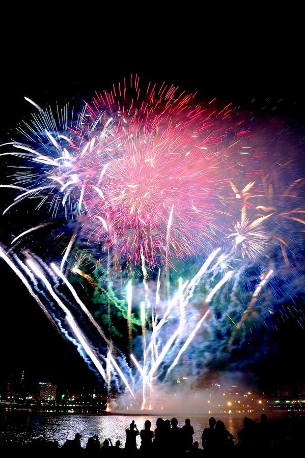 Beautiful and colorful fireworks by the Tamsui River over the sky at night. A view of people watching the firework show. Lights, shadows and smoke with beautiful colors. Beautiful and colorful fireworks by the Tamsui River over the sky at night. A view of people watching the firework show. Lights, shadows and smoke with beautiful colors.