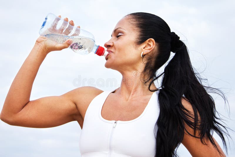 Beautiful fit girl drinking water after exercises