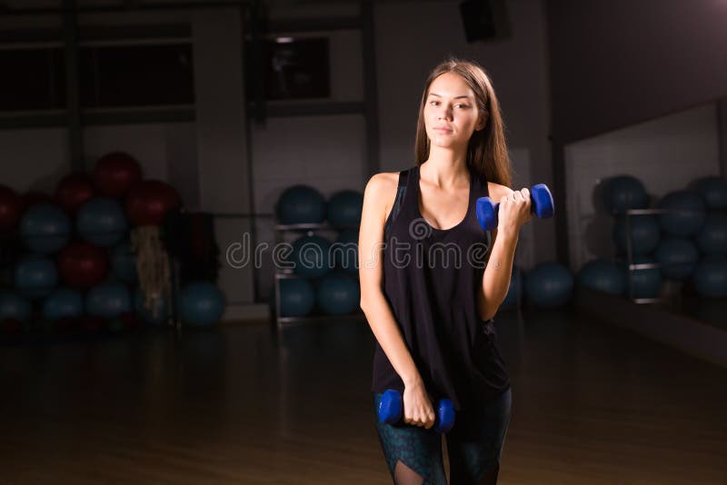 Beautiful fitness woman with dumbbells . Sporty woman lifting light weights. Fit girl exercising muscles. Fitness and