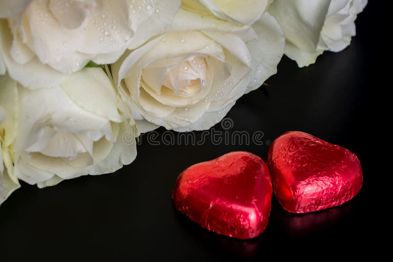 Beautiful flowers on black background with cream roses bouquet and chocolates red heart shaped