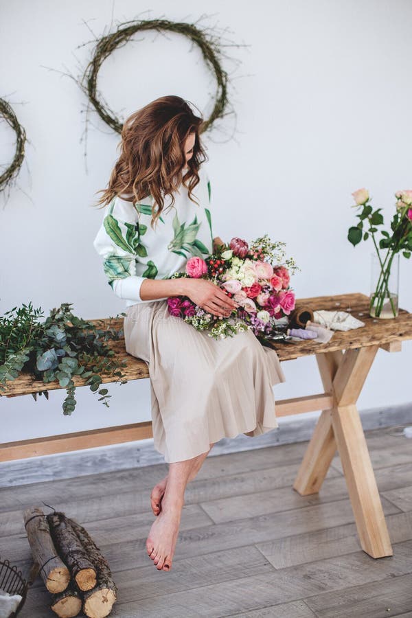 Beautiful flowers pink and white in a vase on a wooden table in a bright room. The girl florist makes a bouquet. Beautiful flowers pink and white in a vase on a wooden table in a bright room. The girl florist makes a bouquet.