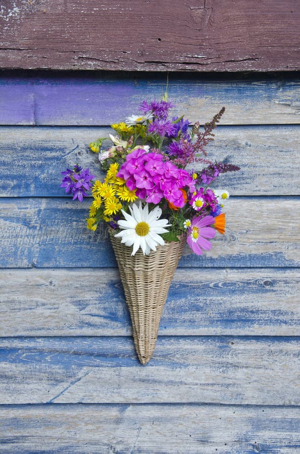 Beautiful flowers in wicker basket on old wooden wall