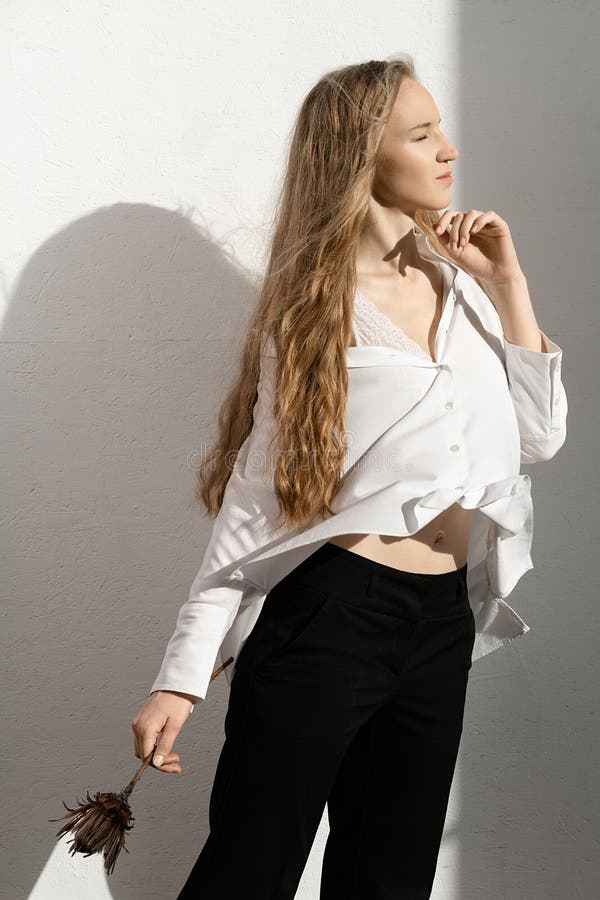 Beautiful fresh blonde model in white shirt and black trousers with flower in hand royalty free stock images Beautiful fresh blonde model in white shirt and black trousers with flower in hand royalty free stock images