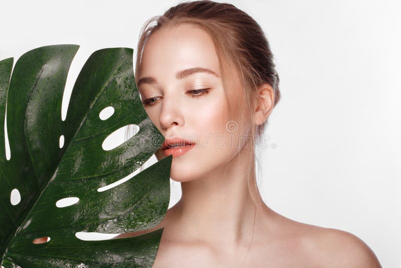 Beautiful fresh girl with perfect skin, natural make up and green leaves. Beauty face.