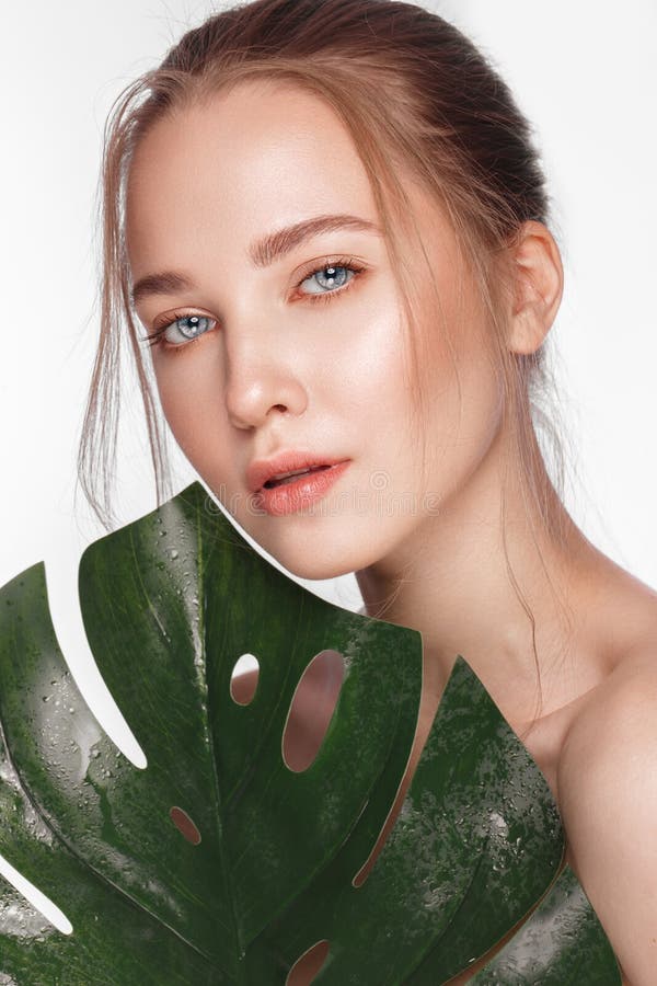 Beautiful fresh girl with perfect skin, natural make up and green leaves. Beauty face.