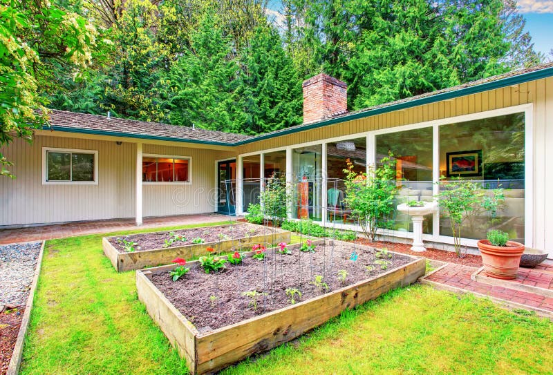 Beautiful front yard landscape with vegetable garden and red tile walkway.