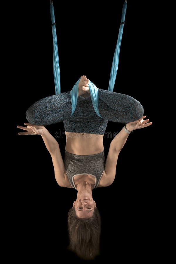 Beautiful funny young woman yoga instructor practicing fly yoga on black background. Vertical frame. Aerial anti-gravity yoga stock photos