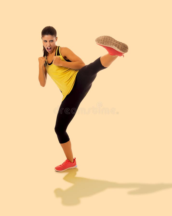 Beautiful and furious girl in fitness clothes training martial arts kick attack looking angry and upset in sports, self defense an stock photography Beautiful and furious girl in fitness clothes training martial arts kick attack looking angry and upset in sports, self defense an stock photography